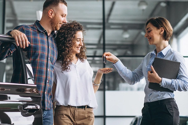 Couple receiving car keys from a sales woman